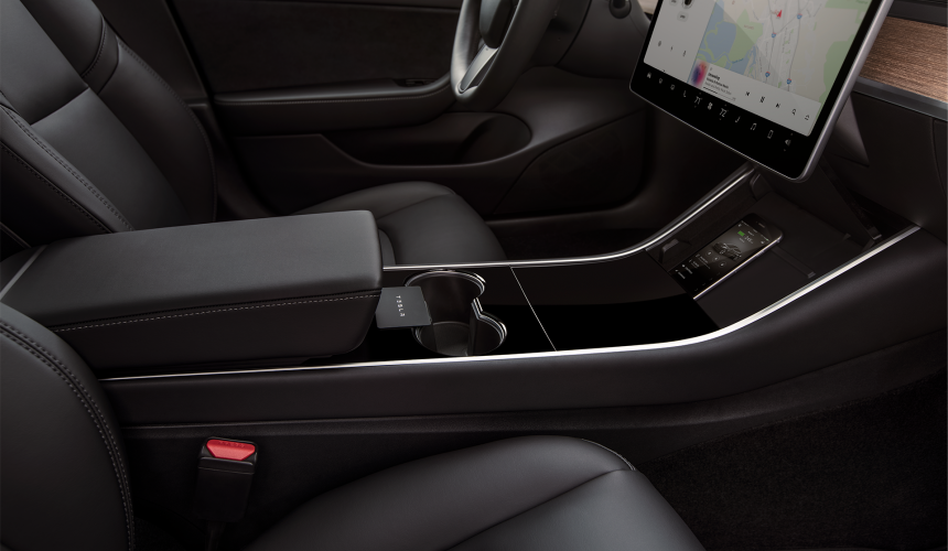 The dash section of a Tesla Model 3, with key-card and smart phone.